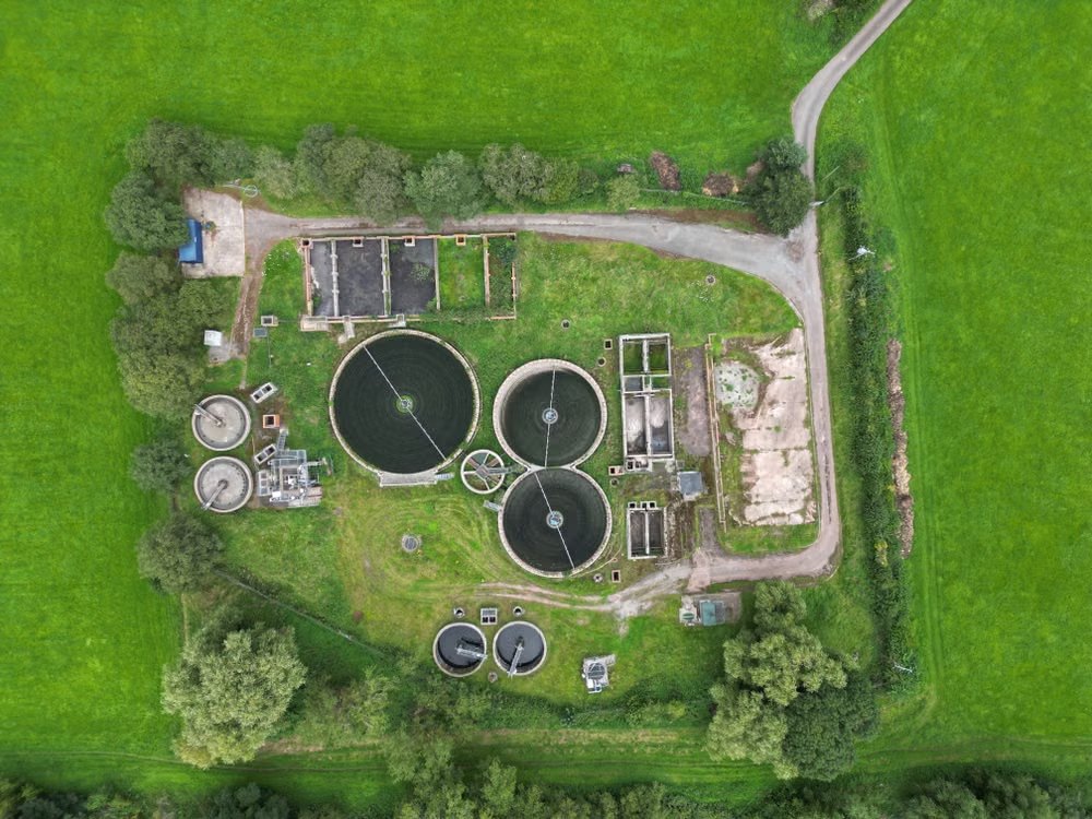 Aerial view of a small wastewater treatment plant surrounded by green fields