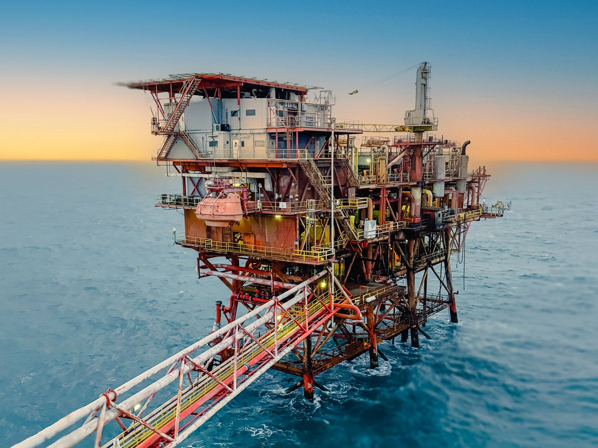 Offshore oil and gas platform at dusk, with a bridge walkway in the foreground